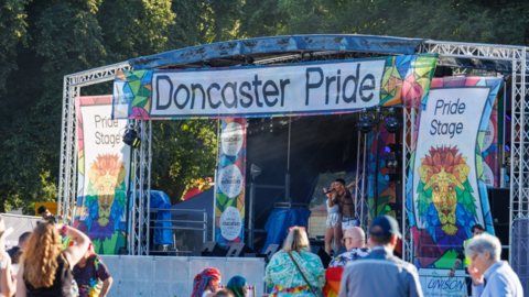 Outdoor music stage with Doncaster Pride banner across the top