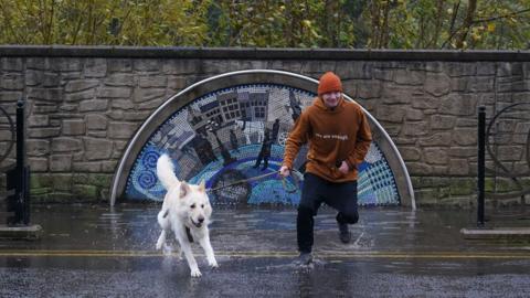 man with dog walking through a puddle in Brechin