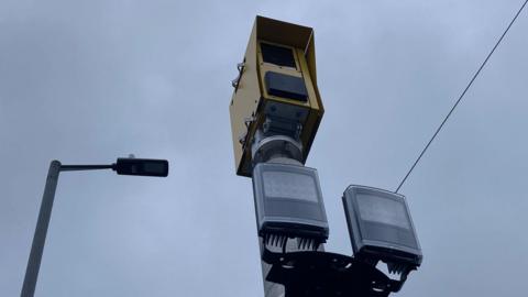 A yellow-coloured metal camera box with two plastic sensor below it