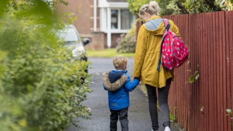 A parent and child walk to school