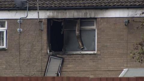 Smoke damage outside a property. Part of a window has come off.