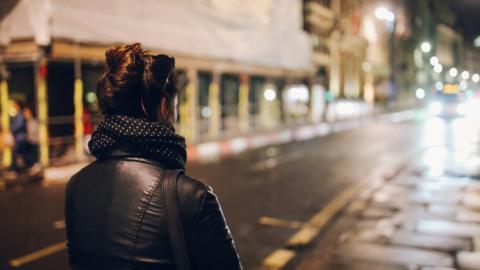 Stock image of a woman walking alone at night