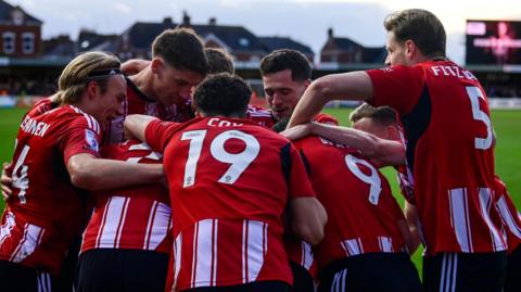 Pierce Sweeney is mobbed by his team-mates after scoring a rare goal for Exeter City