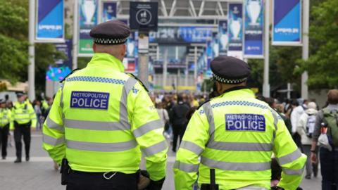 Two police officers stand with their backs to the camera