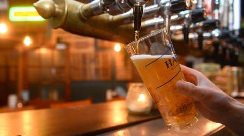 A pint of beer being poured from a set of pumps inside a pub