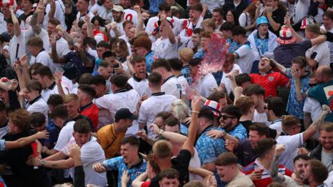 A crowd of men in football shirts jump and wave their arms in celebration at the theFans Central Park Fan Park in Newcastle watching the UEFA Euro 2024 Group C match between Denmark and England. 