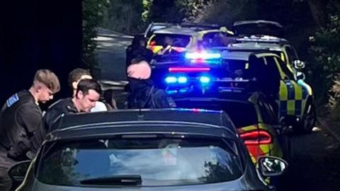 Police cars and officers and three police officers and a man being arrested 