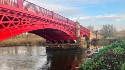 An ironwork bridge, painted red, with brickwork and railings visible.