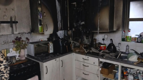A kitchen after a fire, with blackened cupboards. 