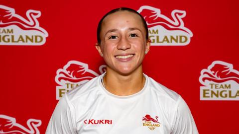 Ruby White standing smiling at the camera, wearing a white 'Team England' tshirt