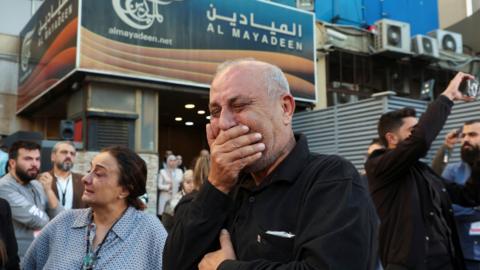 Colleagues of the two Al Mayadeen journalists, who Lebanese officials say were killed by an Israeli strike in southern Lebanon, mourn outside the channel's office in Beirut, Lebanon (21 November 2023)