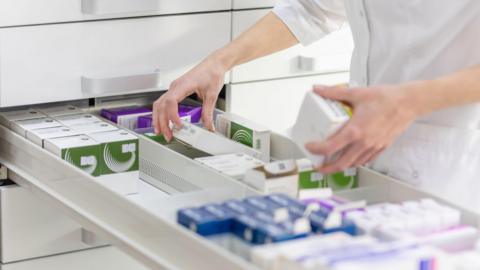 Pharmacist looking through draw of prescription drugs