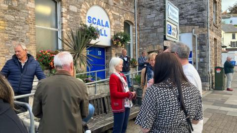 People waiting outside Scala Hall in Brixham where the meeting is being held 