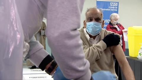 Man with sleeve rolled up, waiting for vaccine