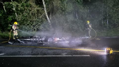 Firefighters using hosereel jets either side of the wreckage