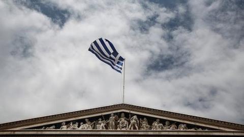 A Greek flag against a bleak sky