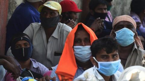 Migrant workers wait outside the Chhatrapati Shivaji Maharaj Terminus railway station