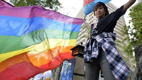 This picture taken on November 17, 2016 shows a supporter of same-sex marriage holding a rainbow flag outside the Parliament in Taipei.