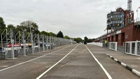 The pit lane at the grandstand for the Manx Grand Prix. It is empty and has the multi-storey red brick grandstand building looking down on it.