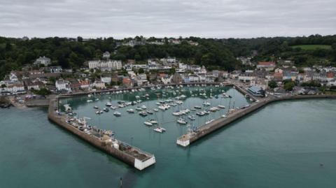 A small granite harbour at high tide, with boats in the harbour and a small village behind.