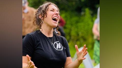 A woman with dark hair and a black shirt singing.