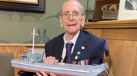 Desmond Burrows holding a replica Navy vessel