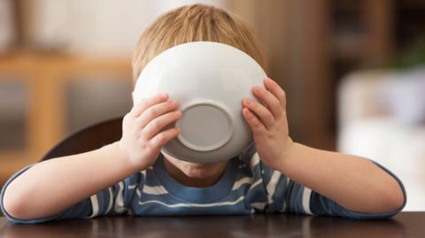 Boy with bowl in front of face