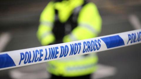 Generic shot of a police cordon, with an officer out of focus in the background