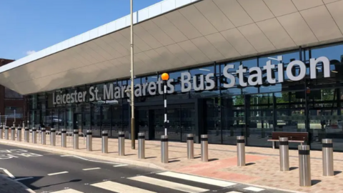 The glass front of the bus station with its name in large silver letters on the exterior