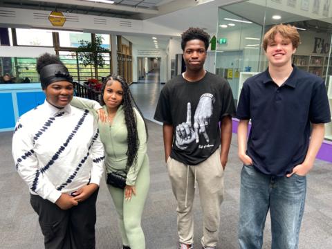 GCSE students stand in a row smiling at the camera