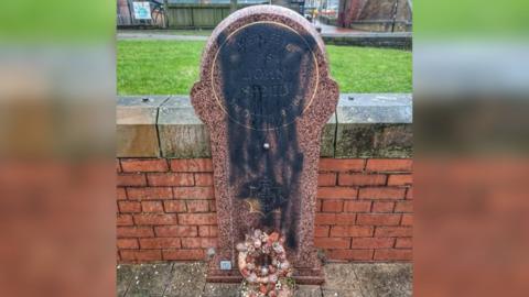 The memorial stone to Sgt John Speed showing black paint sprayed on the stone. 