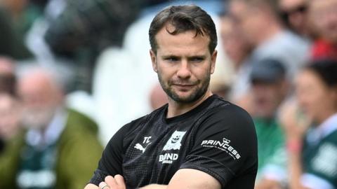 Tom Cleverley with his arms folded, standing on the touchline