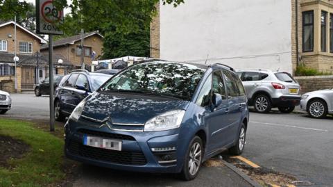 A car parked diagonally on a path.