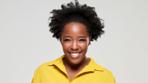 A headshot of Kimberley Wilson wearing a yellow shirt against an off-white background