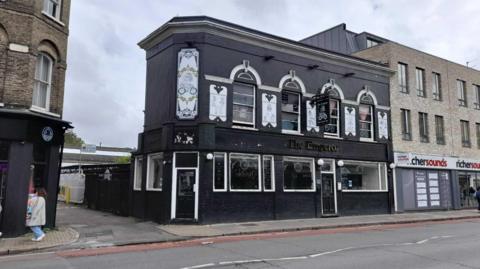 The Emperor Pub in Cambridge. It is a two-storey building with a black front and white detailing around the windows. It stands next to a Richer Sounds store.