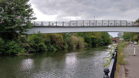 A white footbridge with railings across a river