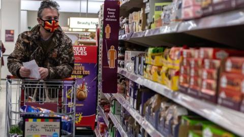 A man wearing a face mask shops in a Sainsburys supermarket