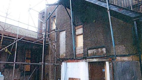 House with scaffolding and boarded up windows as worked on by Christopher Newman