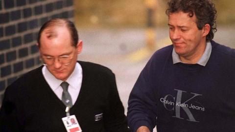 Barry Bennell, handcuffed to a custody officer, in 1998