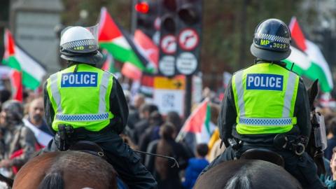 Two police officers on horseback seen from behind at a pro-Palestinian march