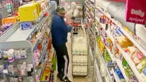 Man throwing substance on another man in a corner shop.