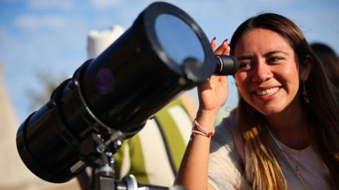 A woman in Mexico observes the Sun with a telescope ahead of the total eclipse