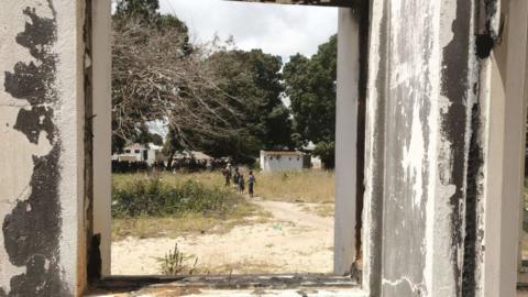 Children are seen through a broken window in Palma, Mozambique - September 2022