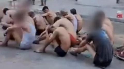 Palestinian men in their underwear, sat on the ground