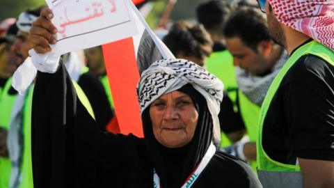 An Iraqi protester holds a sign reading "Brother don't kill me"