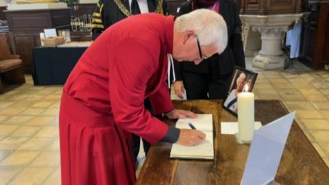 DEan of Derby Cathedral signing the book of remembrance