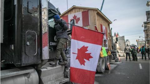 A Canadian trucker driver holds a flag