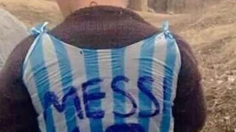 A boy wearing a Lionel Messi football shirt made out of a carrier bag