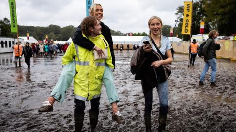The young adults walk through mud at music festival