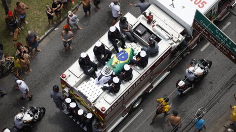 Fire truck carrying Pele's coffin which is draped in a Brazil flag